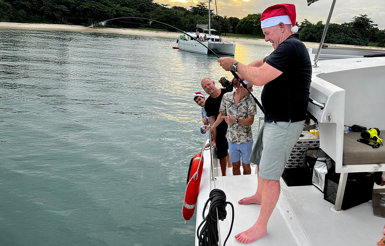 fishing off side of AQUAHOLIC with christmas hat