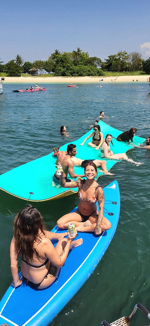 AQUAHOLIC Guests and a dog enjoying a drink on AQUAHOLIC's watertoys, watermat and stand-up paddleboards