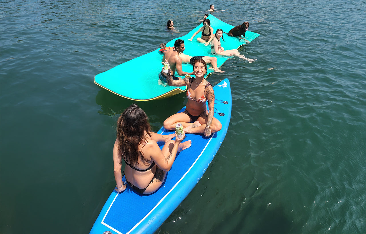 AQUAHOLIC Guests and a dog enjoying a drink on AQUAHOLIC's watertoys, watermat and stand-up paddleboards